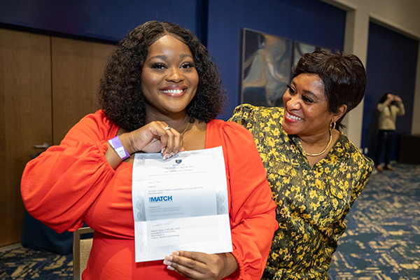 ETSU medical students joyfully display their match letters during the Quillen College of Medicine Match Day celebration.