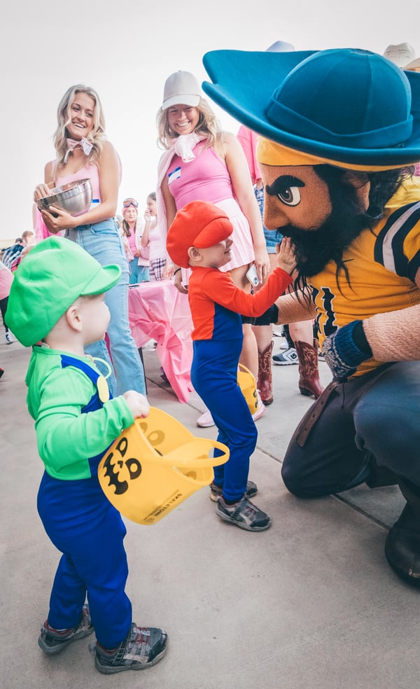 Bucky gives high-fives to tiny trick-or-treaters.