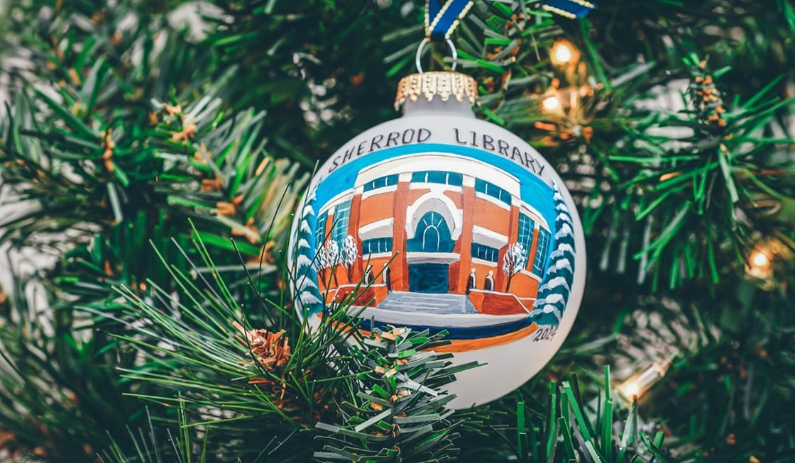 A white globe holiday ornament featuring a hand-painted landscape of Sherrod library accented by winter snow. 