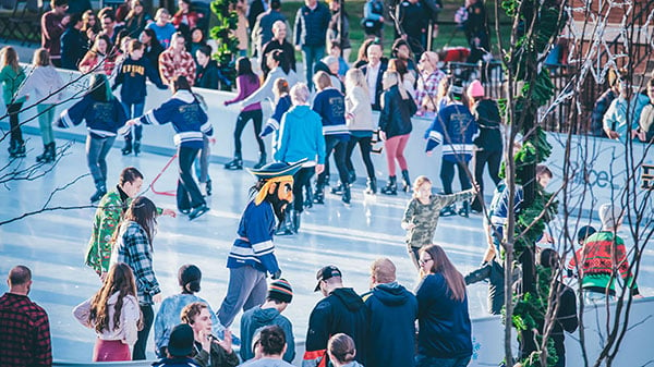 Bucky, surrounded by students and members of the community, skates on the new ice-skating rink at University Commons.