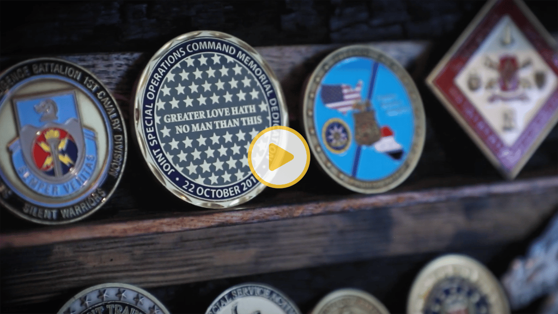 Several military medals and challenge coins on a shelf. 