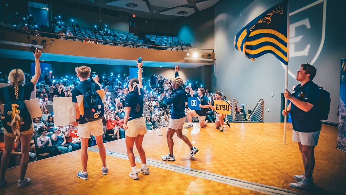 Orientation leaders on stage are firing up a crowd of incoming students 